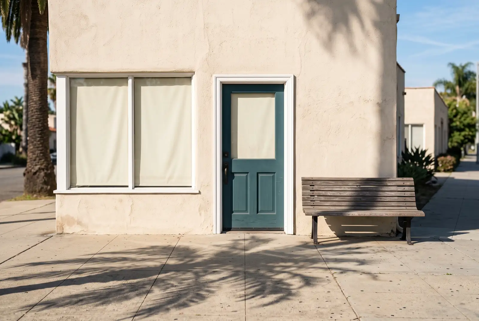 Closed office door with drawn blinds on a quiet sunlit Los Angeles sidewalk on a Sunday morning